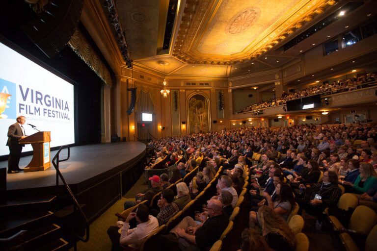 Virginia Film Festival event: Man speaking at podium in packed theater.