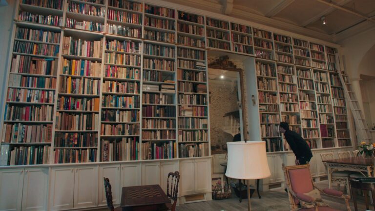Floor-to-ceiling library with a man browsing books.