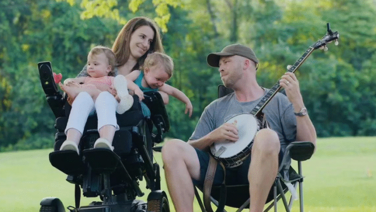 Family portrait: Quadriplegic mom with twins, dad playing banjo outdoors.