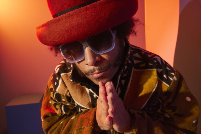 Boots Riley wearing a red hat and patterned jacket, promoting his new Amazon Prime series.