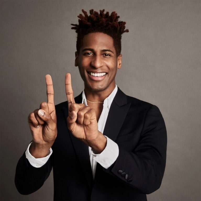 Jon Batiste smiles, holding up two fingers. Virginia Film Festival 2023