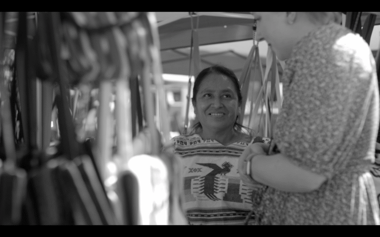 Woman smiles at an outdoor market in Charlottesville film.