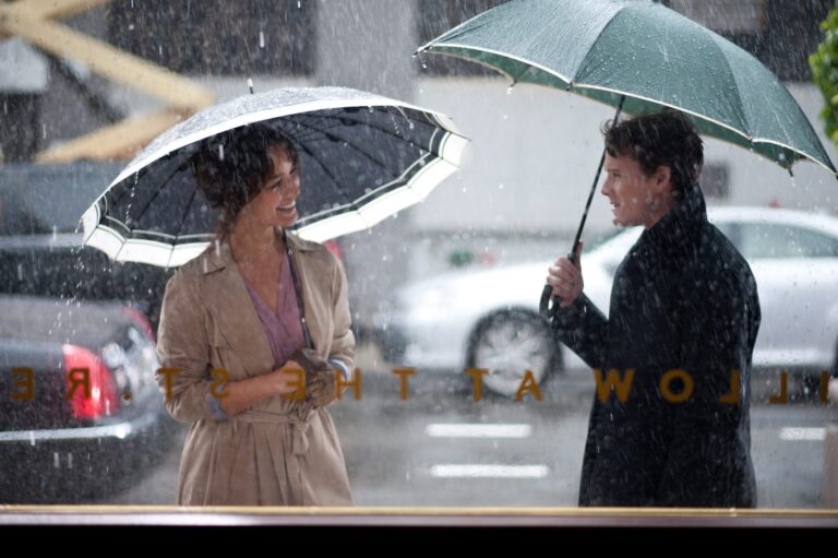 A man and a woman on the sidewalk under umbrellas in the rain.