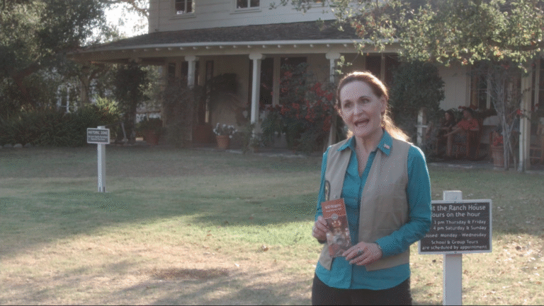 Docent at Will Rogers Ranch State Historic Park holding brochure.