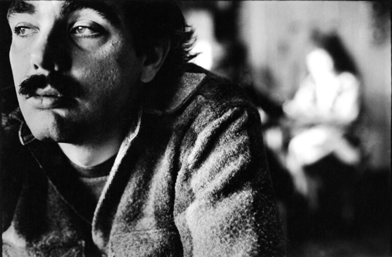 Black and white portrait of American poet Larry Levis in a jacket, looking to the left.