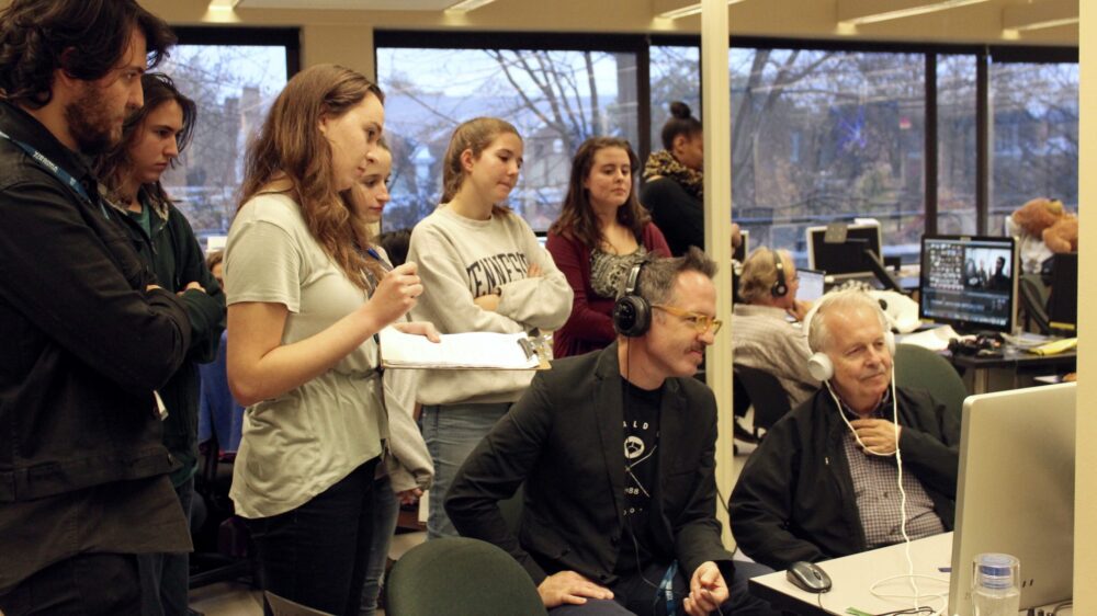 Group watching a screen, possibly reviewing film footage for the Adrenaline Film Project.