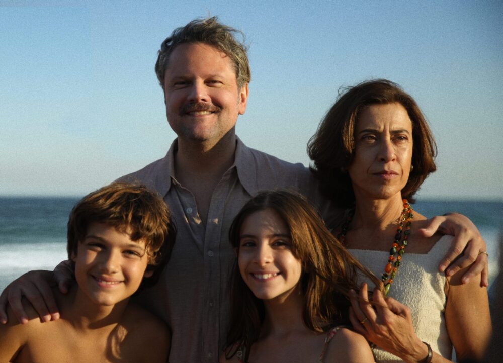 Family portrait on a beach with parents, son, and daughter smiling at the camera.