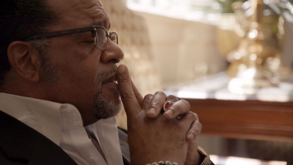 Thoughtful Black man with glasses and a large ring.