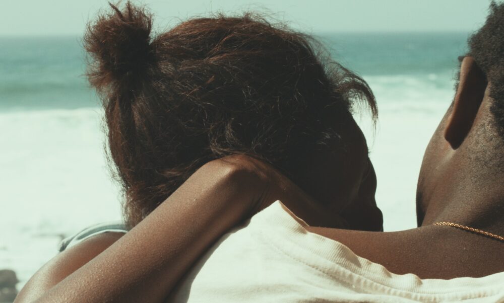Couple looking out at the ocean, evoking the themes of the film "Atlantics.