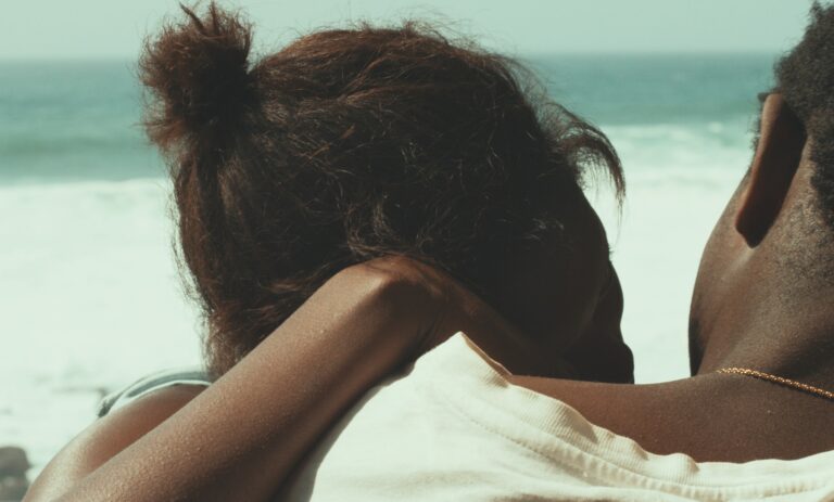 Couple looking out at the ocean, evoking the themes of the film "Atlantics.