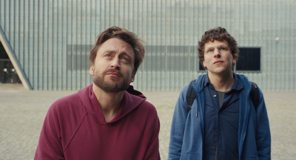 Two men look up, possibly reacting to something, in "A Real Pain.
