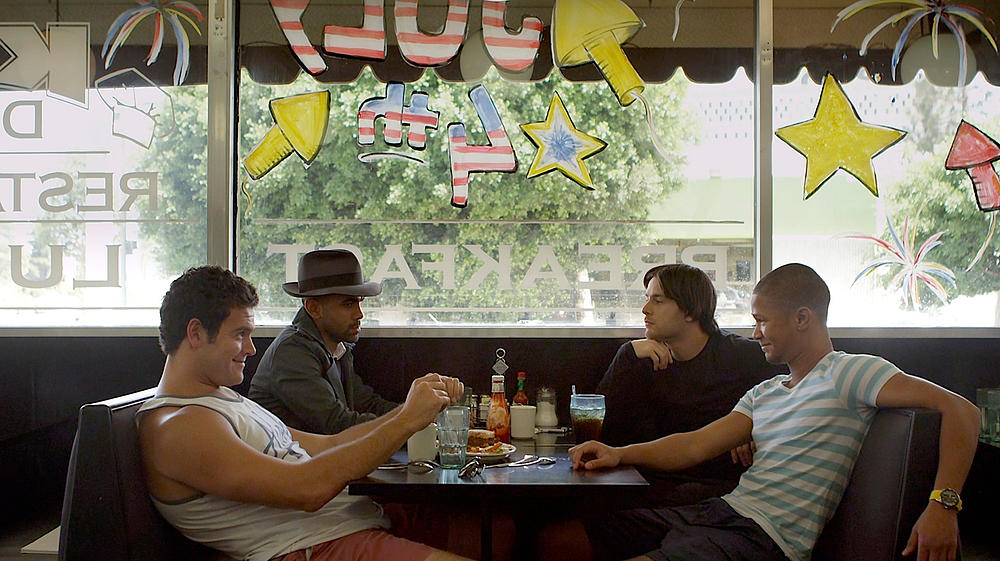Four men at a diner, celebrating July 4th. "Breakfast" visible in the window.