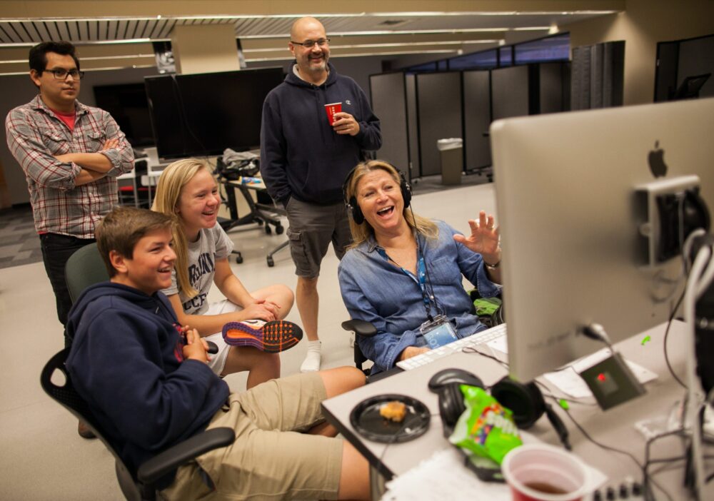 Group collaborating on the Adrenaline Film Project, smiling at a computer screen.