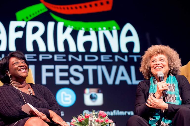 Angela Davis at Afrikana Film Festival. Two women laughing on stage at the event.