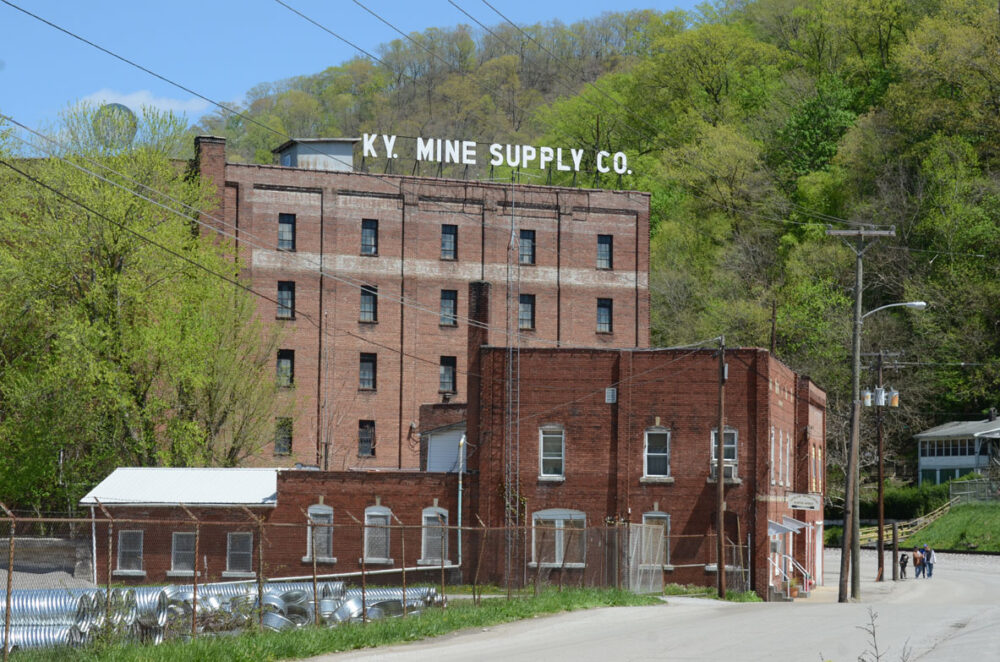 KY Mine Supply Co. building with red brick in a green, hilly landscape.