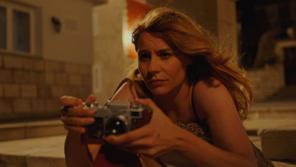 Woman with camera in Aleksi film scene.