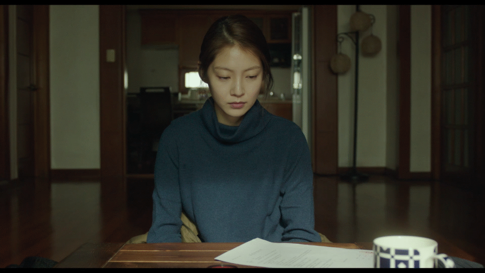 Woman in blue sweater sitting at table with papers.