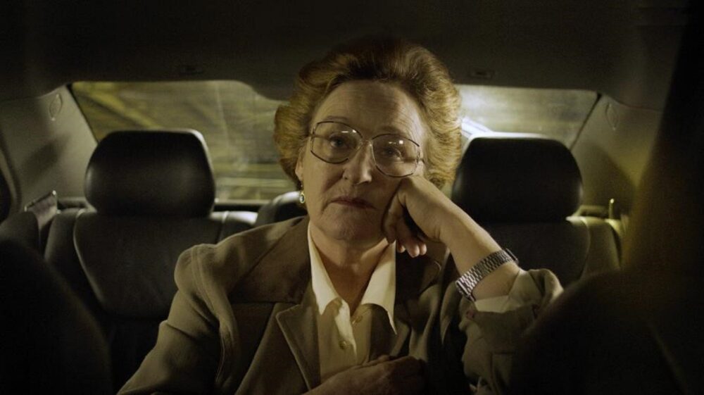 Pensive older woman in a car, perhaps facing problems.