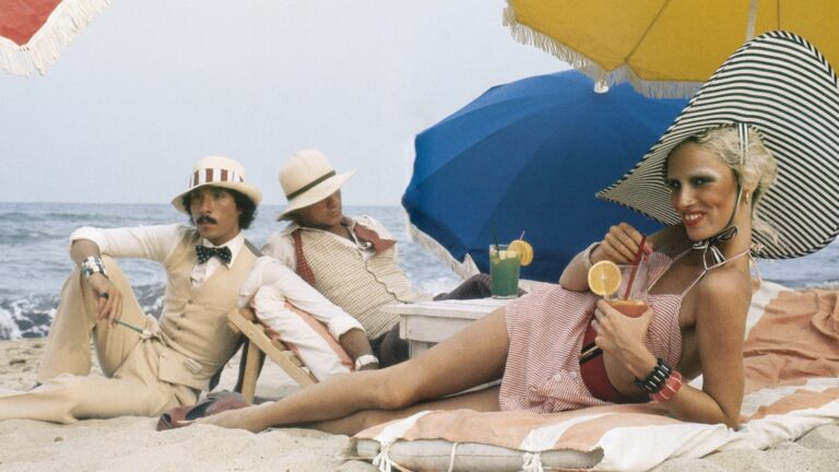 Glamorous beach scene with models in 1970s fashion, reminiscent of Antonio Lopez's style.