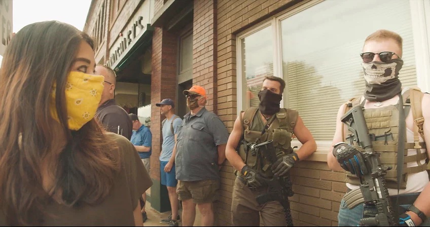 People in Bad Axe, some armed, stand outside a building.