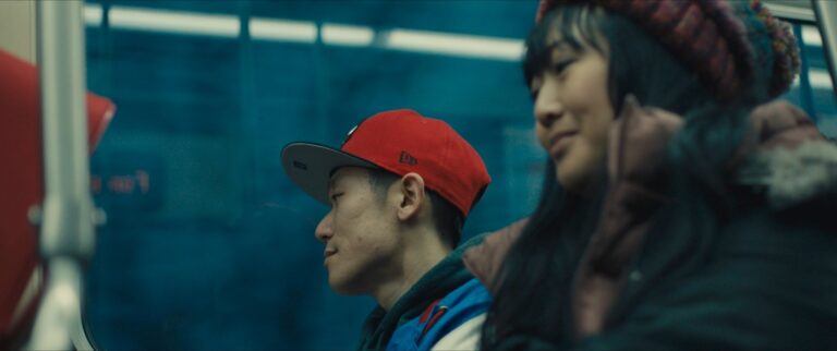 People on a subway, one wearing a red cap.
