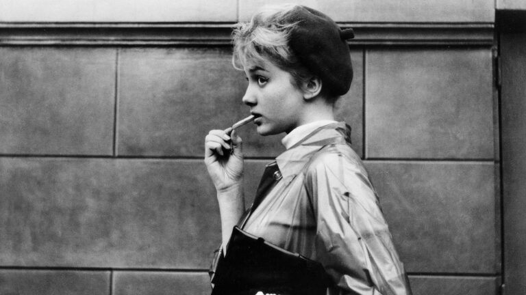 Anna Karina in "Bob Le Flambeur" wearing a beret and raincoat, holding a cigarette.