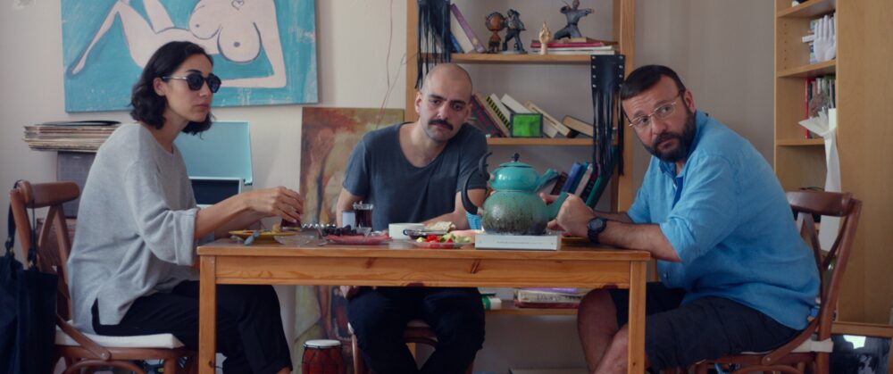 Three people at a table in Kelebekler (Butterflies), enjoying a meal.