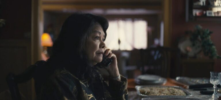 Woman on phone at dining table with food.