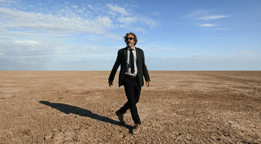 Man in suit walks across cracked desert in "Bardo, False Chronicle of a Handful of Truths.