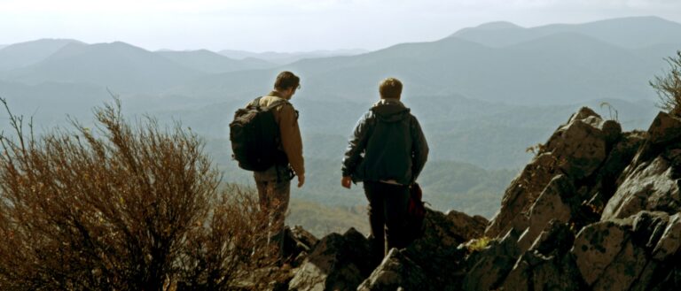 Two hikers overlooking a mountain range.