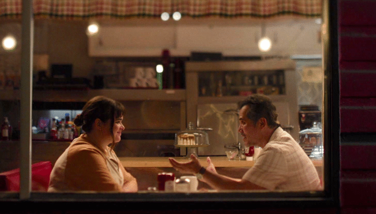 Man and woman talking in a diner booth at night.
