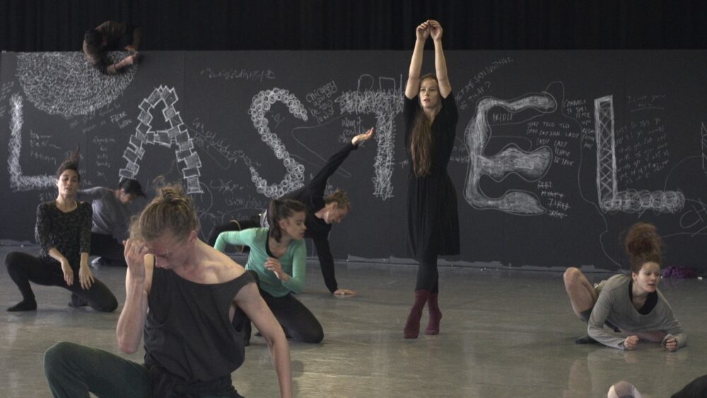 Dancers in motion with "LASTEL" written on the wall.