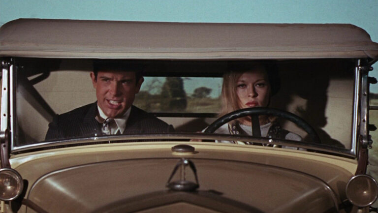 Bonnie and Clyde driving an old car, looking tense.