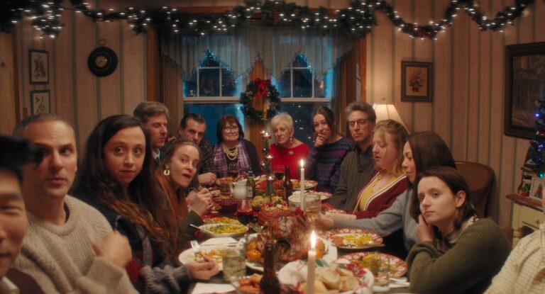 Family gathers around a Christmas Eve dinner table, festive and warm.