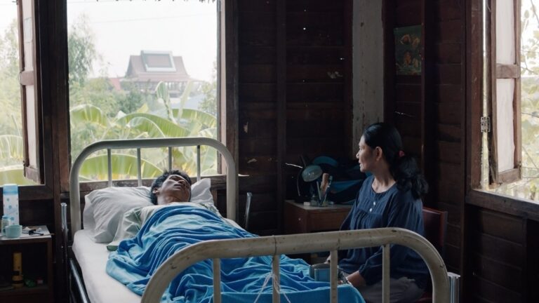 Man in hospital bed, attended by woman, in Apichatpong Weerasethakul's Cemetery of Splendour.