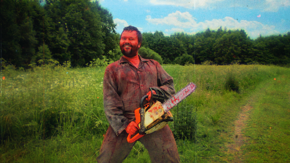 Man covered in blood smiles, holding a chainsaw in a field. Chainsaws Were Singing.
