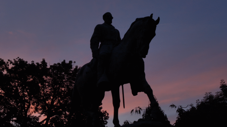 Statue of a man on horseback silhouetted against a colorful Charlottesville sky.