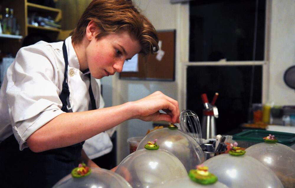 Chef Flynn carefully plating dishes with domes.