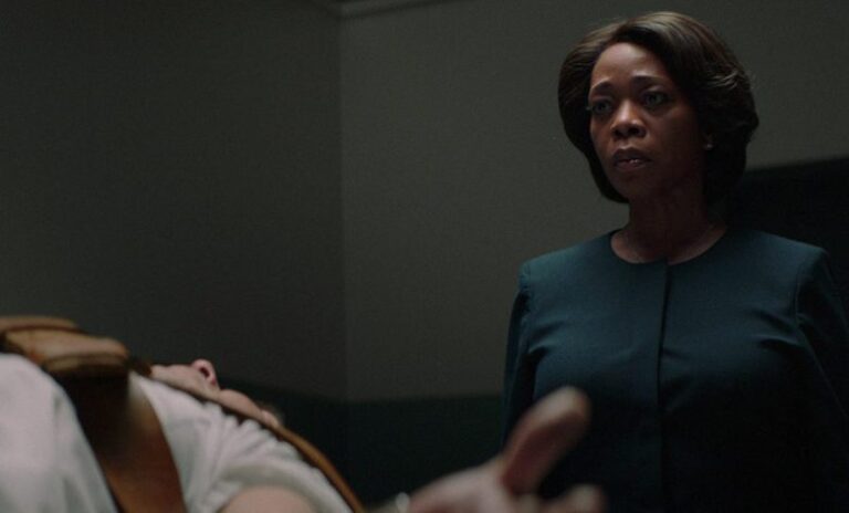 Woman in "Clemency" observes a body on a gurney.