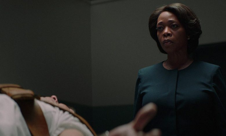 Woman in "Clemency" observes a body on a gurney.