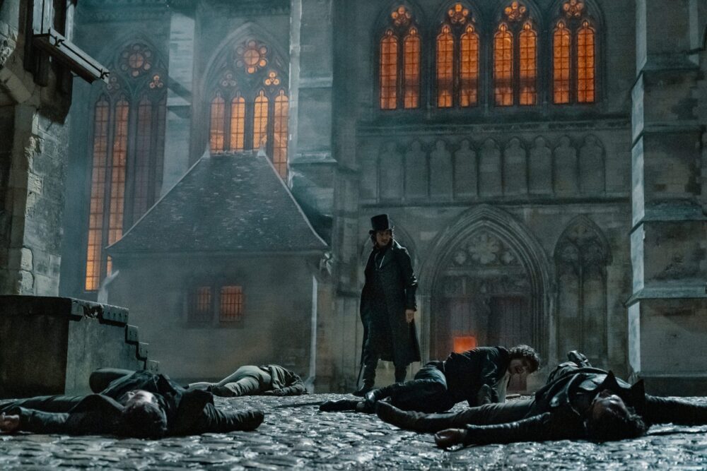 The Count of Monte Cristo stands over fallen men in a courtyard.