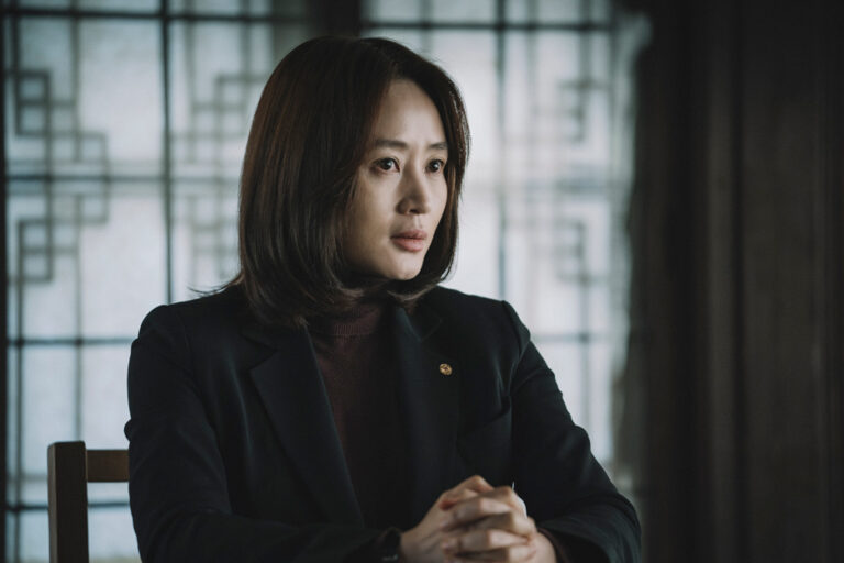 Korean actress Kim Hye-soo in a dark suit and turtleneck, serious expression.