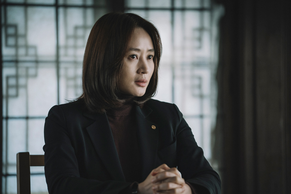 Korean actress Kim Hye-soo in a dark suit and turtleneck, serious expression.
