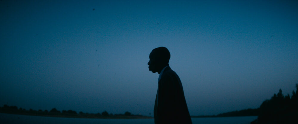 Silhouette of a man against a dark blue sky, possibly related to "Demba.