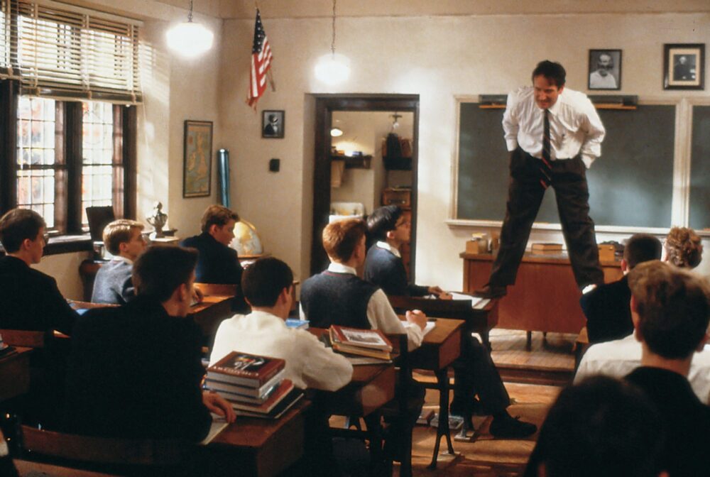 John Keating inspires students in Dead Poets Society, standing on a desk in the classroom.