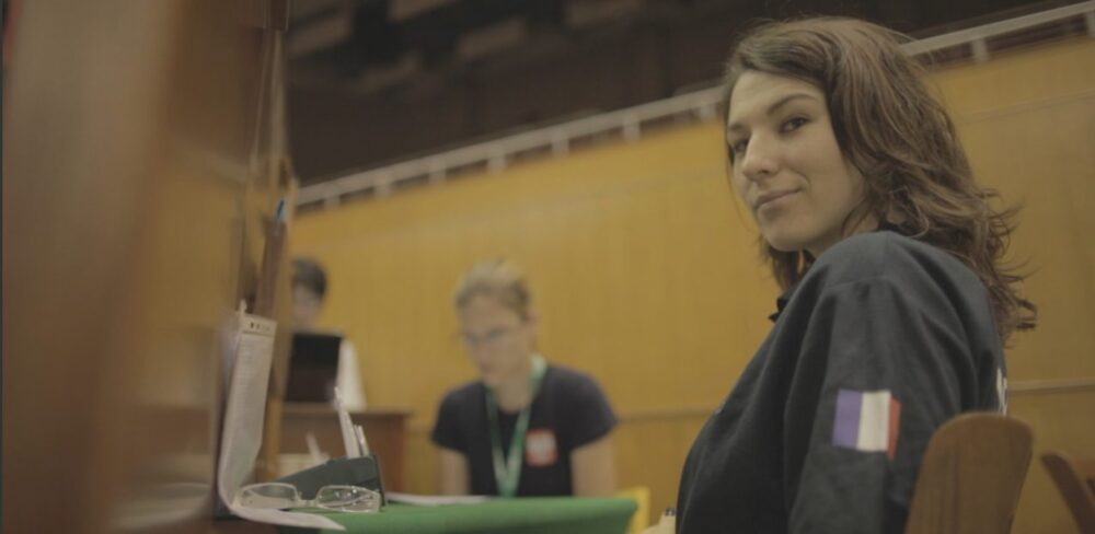 Woman with French flag patch at a bridge tournament, possibly playing Double Dummy.