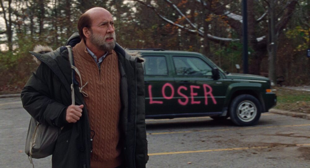 Paul Matthews from "Dream Scenario" looking at a car spray-painted with "LOSER.