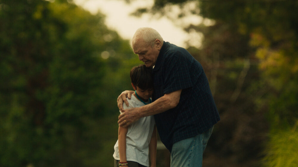 Older man comforting a young boy with his arm around him