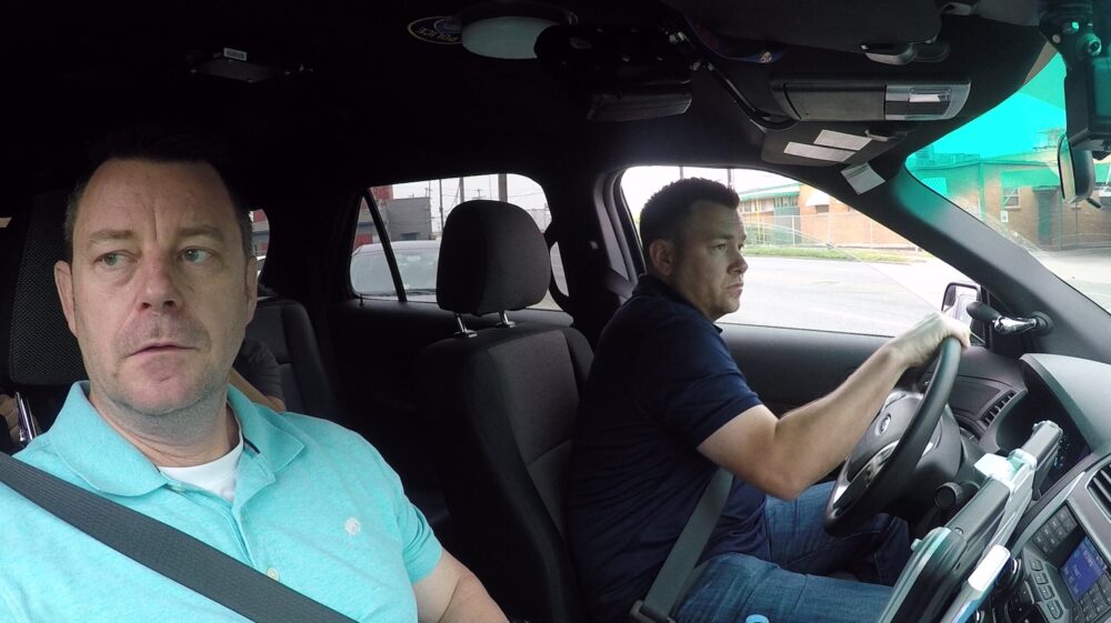 Two police officers, possibly Ernie & Joe: Crisis Cops, in a police car on patrol.