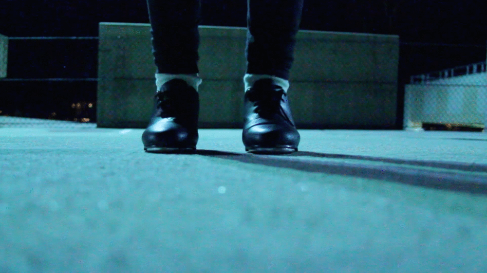 Black tap shoes on a concrete surface, ready for "Educated Feet" dance blog content.